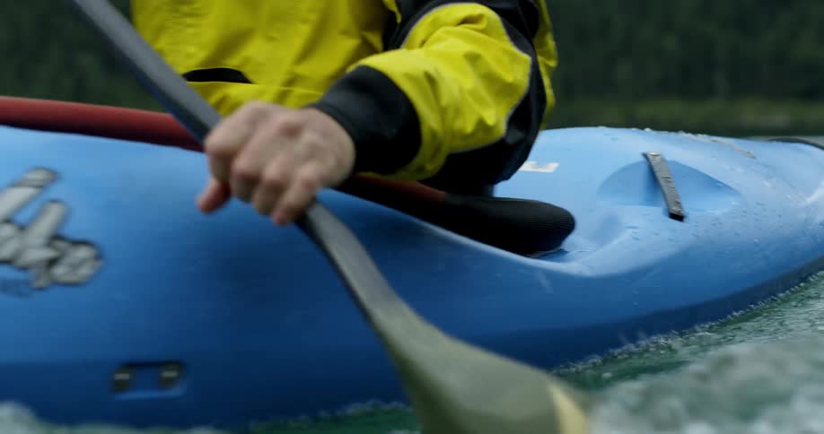A person paddles a blue kayak on a lake