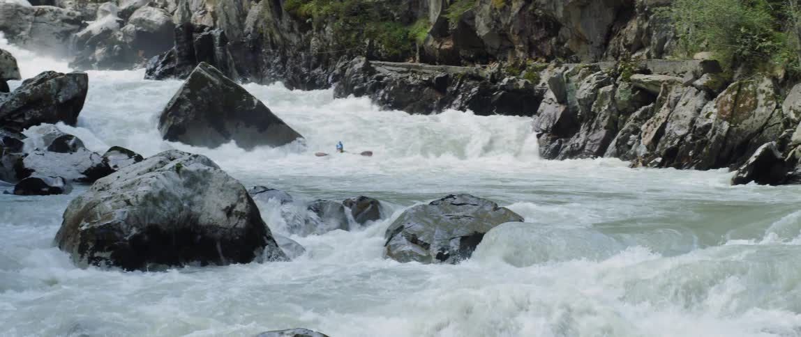 A person in a canoe moving down rough and rocky waves