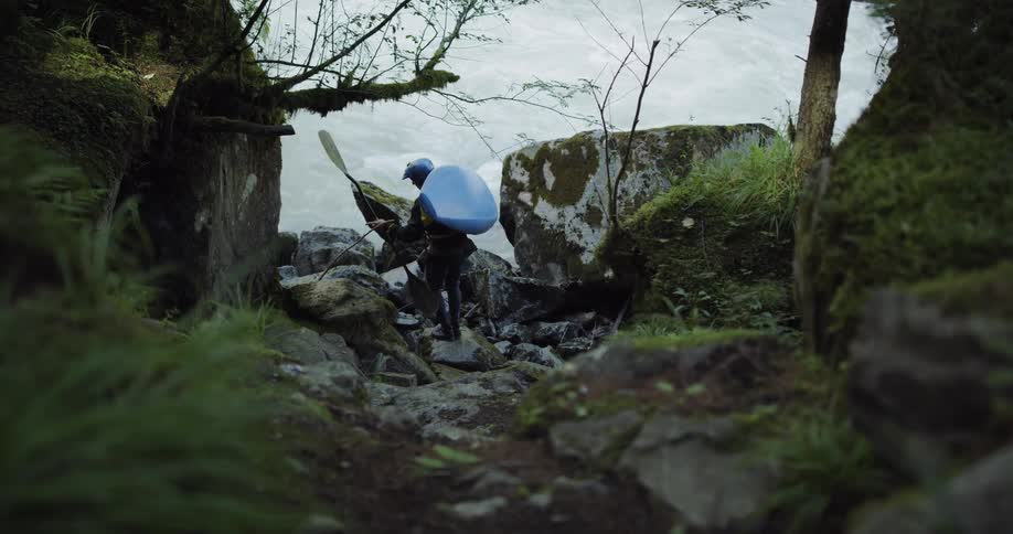 Man carries a kayak and paddles to a river