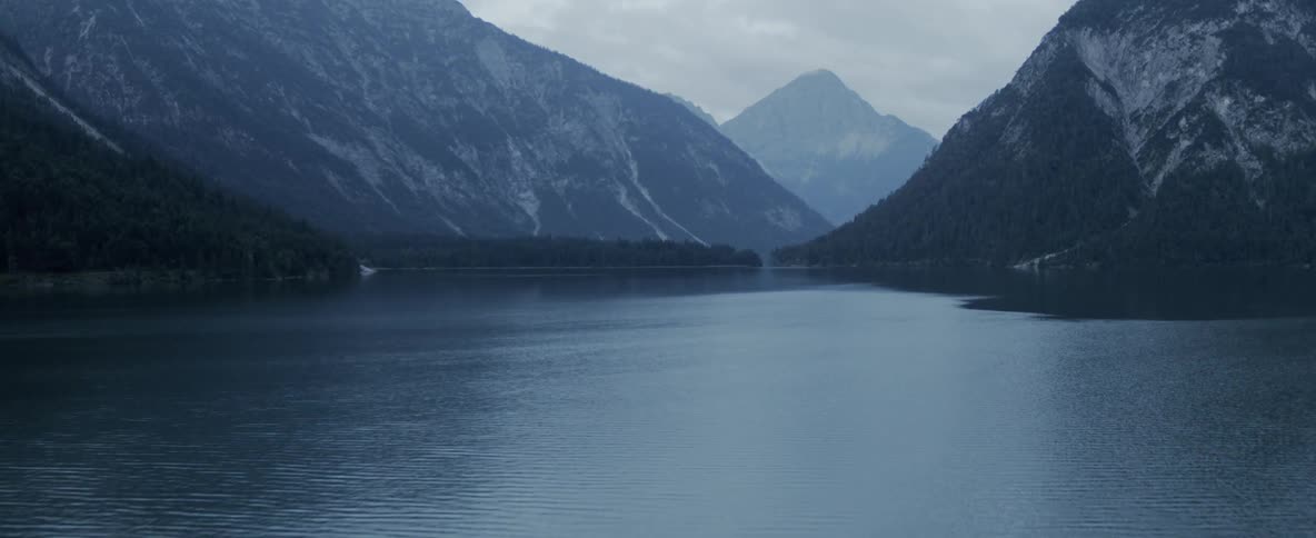 A lake is surrounded by forest covered mountains