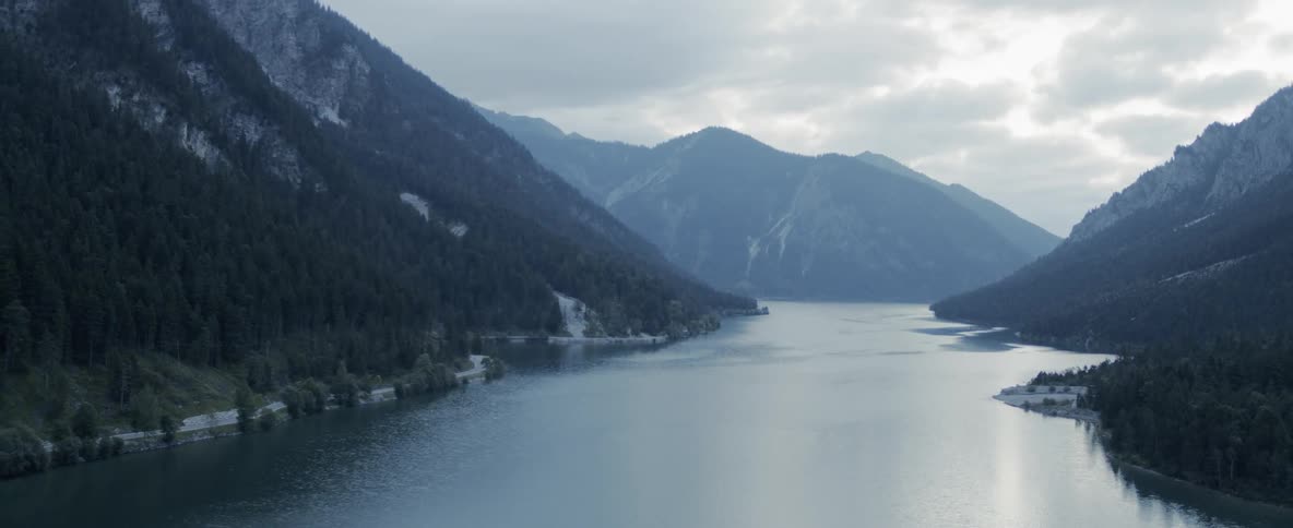Lake in valley between mountains under cloudy sky