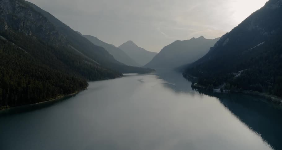 A lake is surrounded by forest covered mountains