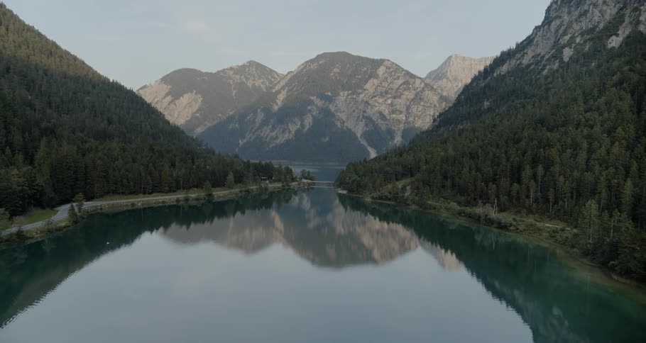 A lake is surrounded by forest covered mountains