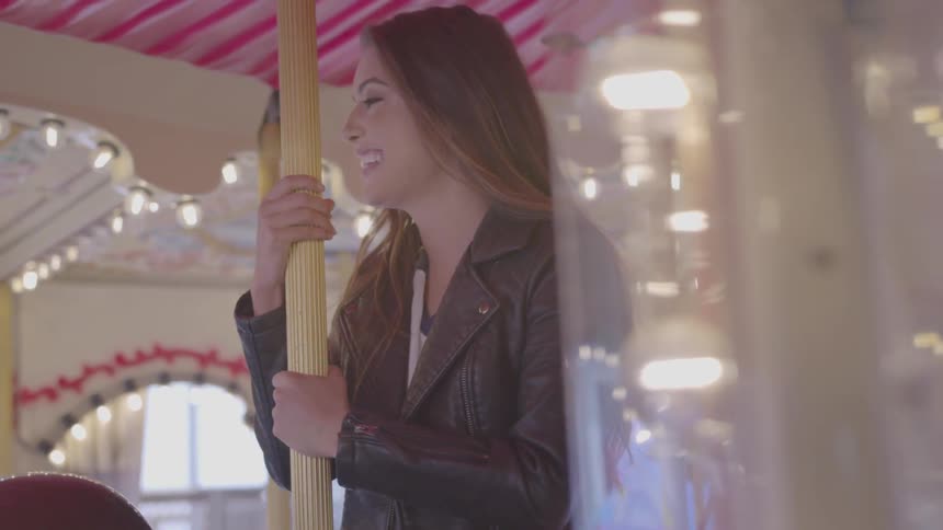 A woman in a leather jacket riding a carousel
