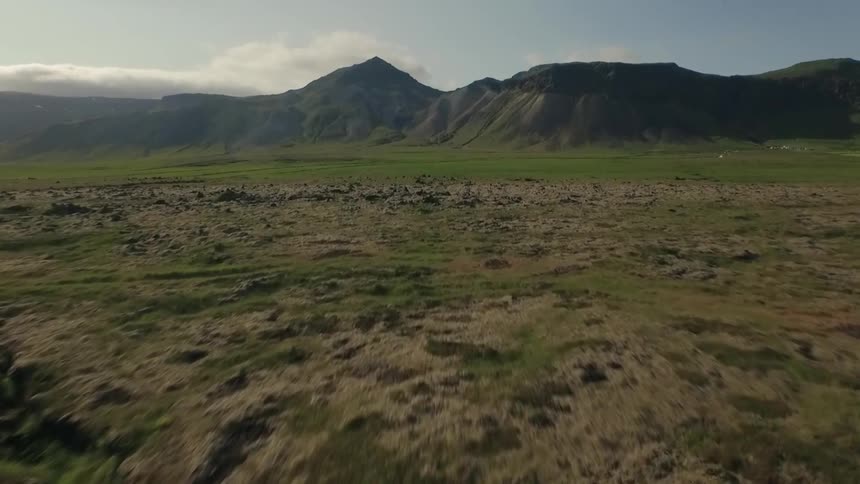 A vast landscape with multiple craters ahead of large mountains