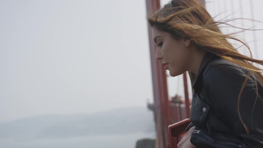 A white woman looks over the side of a bridge