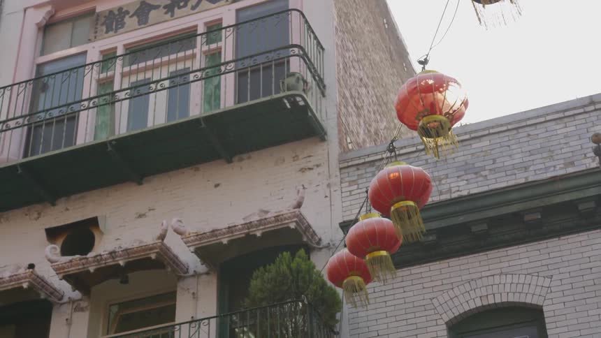 Asian style lanterns hang from a wire attached to a building