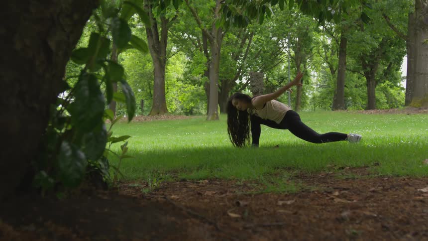 A woman does yoga while in a park