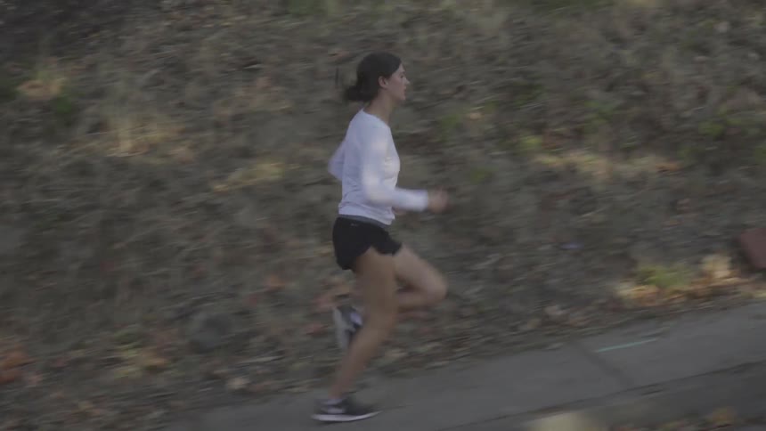 A young white woman runs up a sidewalk