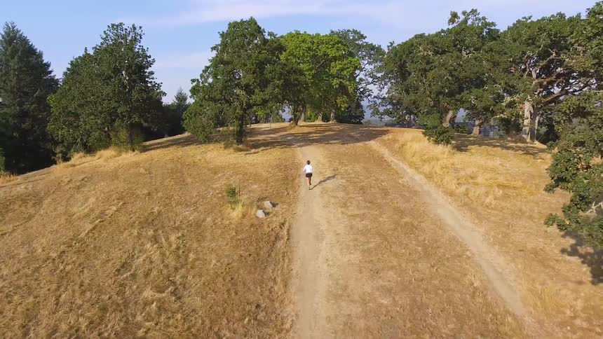 A woman in running shorts jogs on a rural dirt path