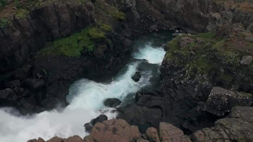 A waterfall flows over a small cliff into a river