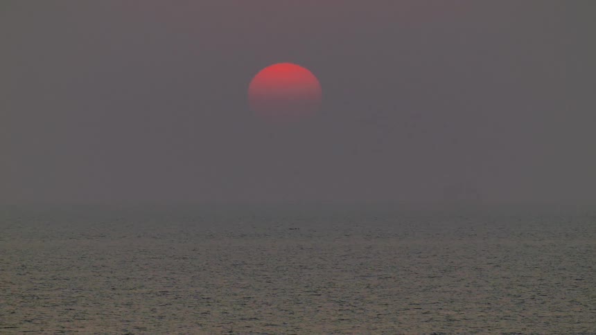 Red sun setting in the horizon over the ocean