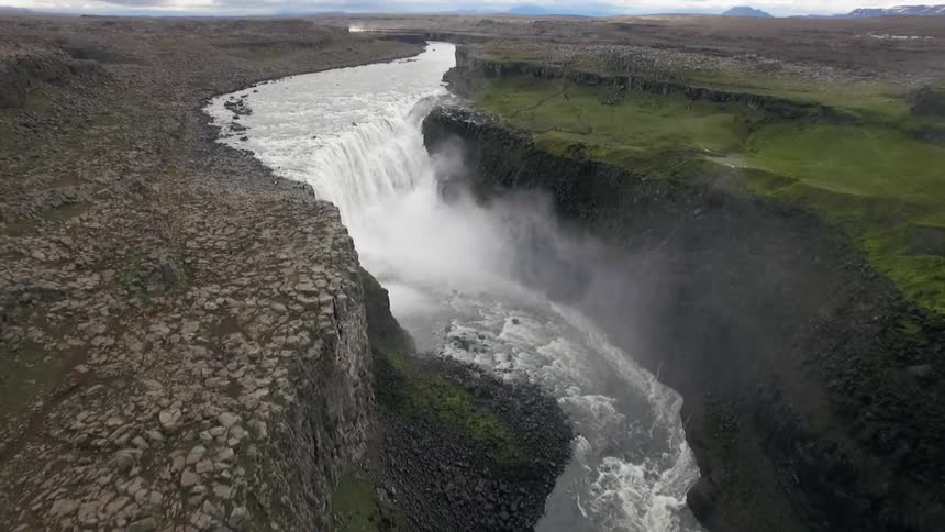 View of a winding river ending in a waterfall crashing down between steep cliffs