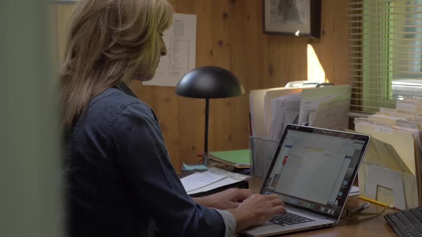 A woman types on a laptop at a desk