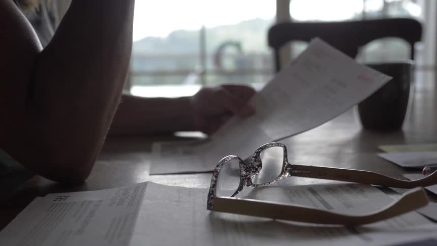 A person setting their glasses down reading documents