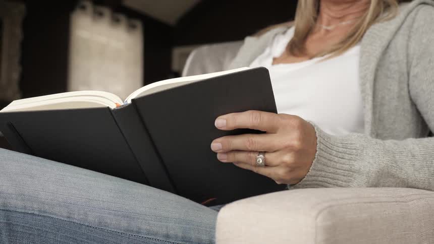 A woman sits in a chair writing something in a journal