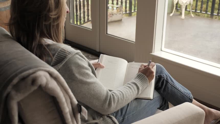 A woman writing in a journal while sitting in a recliner