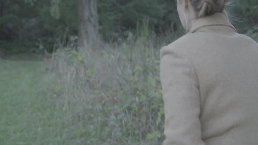 A woman walks through a grassy field