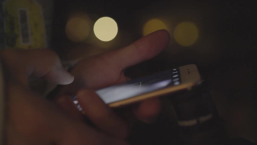 A person watching a video on a smart phone outdoors at night