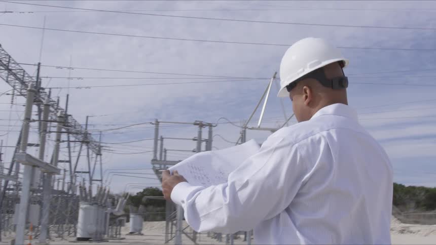 Worker in a hard hat looks at the drawing on a paper in his hands