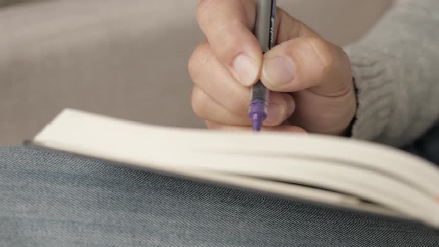 Someone is writing in a notebook with a pen
