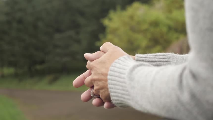 A person leaning over a railing with their hands clasped together