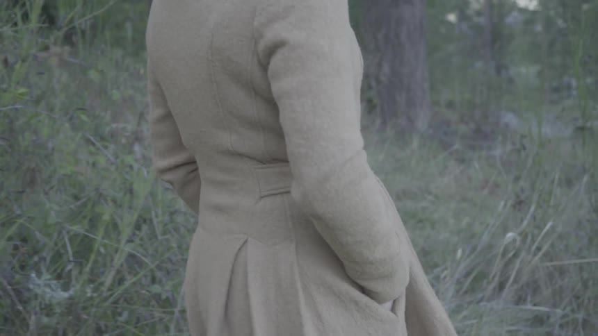 Woman wearing a coat and hands in her pocket walking in the forest