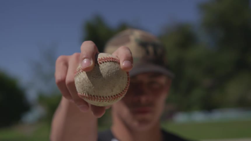 A man holding onto a baseball outdoors