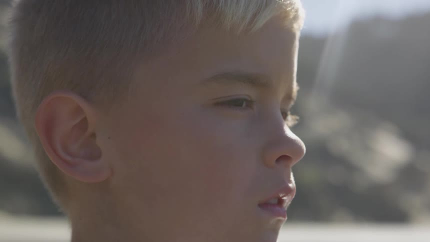 Boy stands outdoors staring