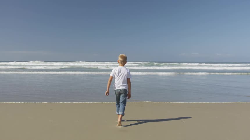 A child skips toward the ocean water
