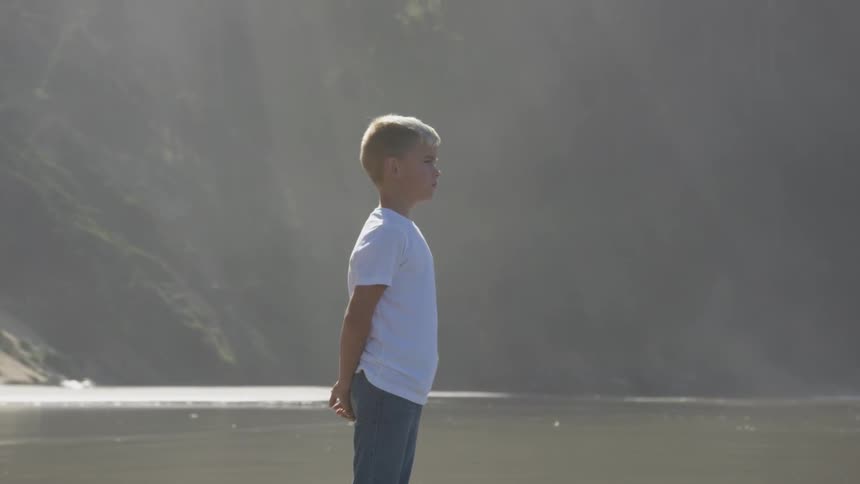 An adolescent boy stands so we see his profile as he looks straight ahead