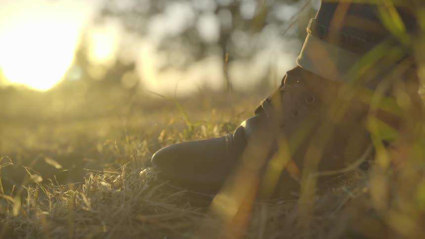 A person in boots stands in a grassy field