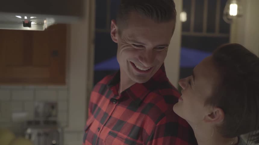 A couple standing side by side look at each other and smile