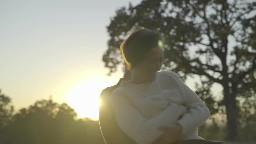 Man hold a woman in his arms and dances with her under the trees