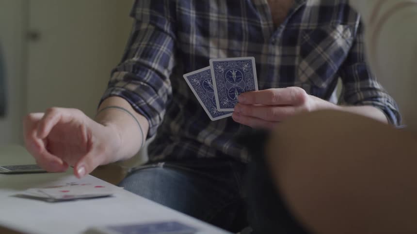 A person lays down playing cards to a table during a game