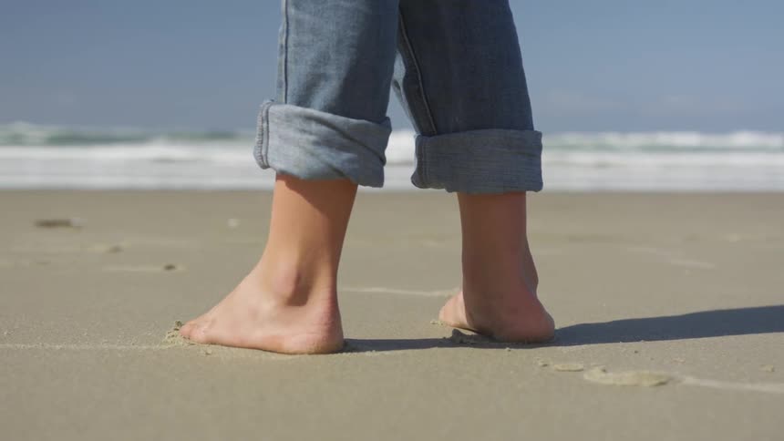 Someone stands on the sand looking out at the ocean