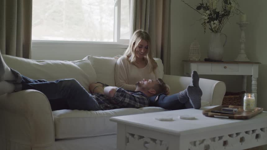 A man lays on a couch with his head resting in a woman's lap
