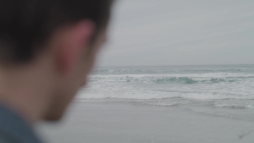 A man standing on a beach on a cloudy day