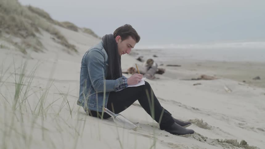 Man sits on beach writing