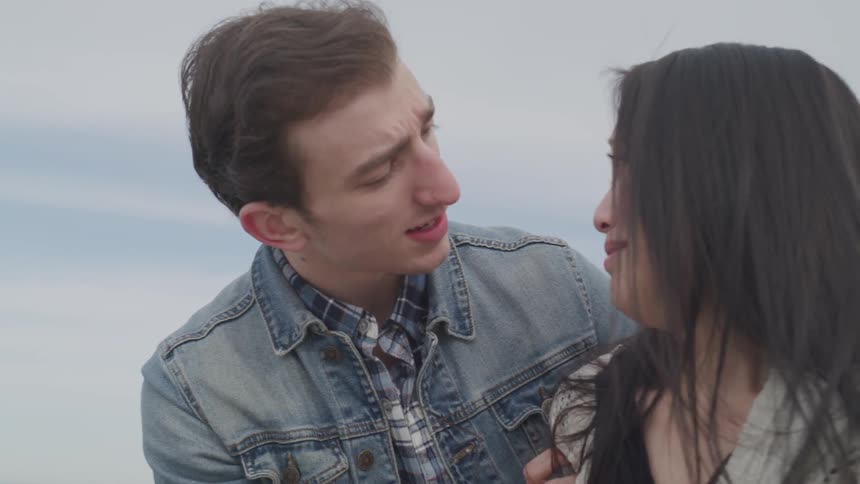 A man consoles a crying woman on the beach