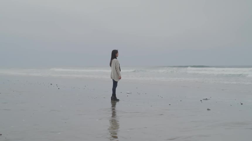 A woman standing at the edge of the ocean