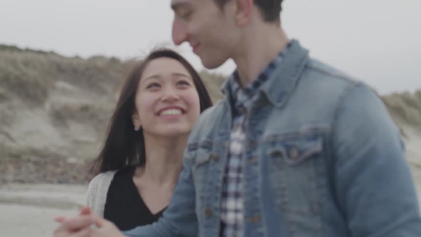 A man and woman walk along holding hands