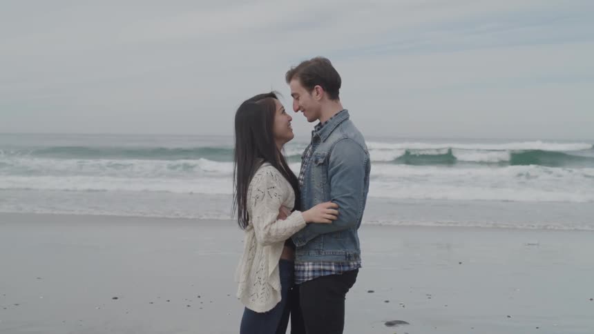 A man and a woman holding each other on the beach