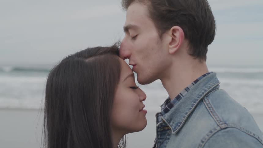A man kisses a woman on the forehead