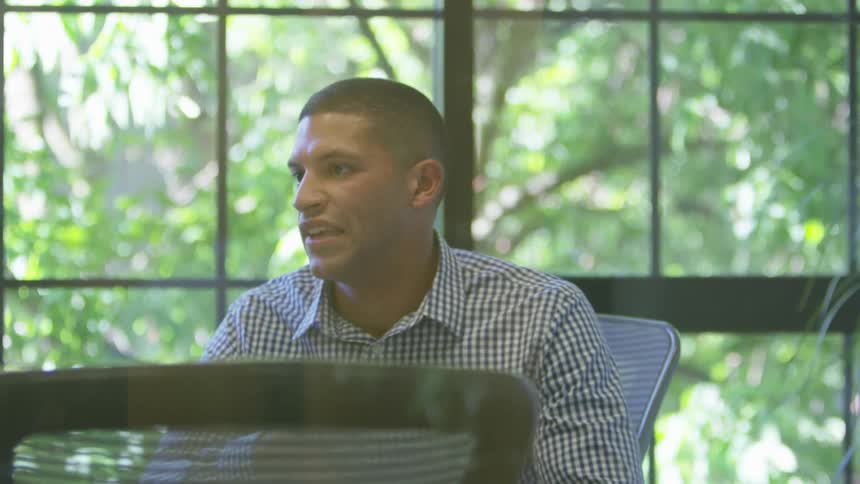 A man speaking while sitting indoors