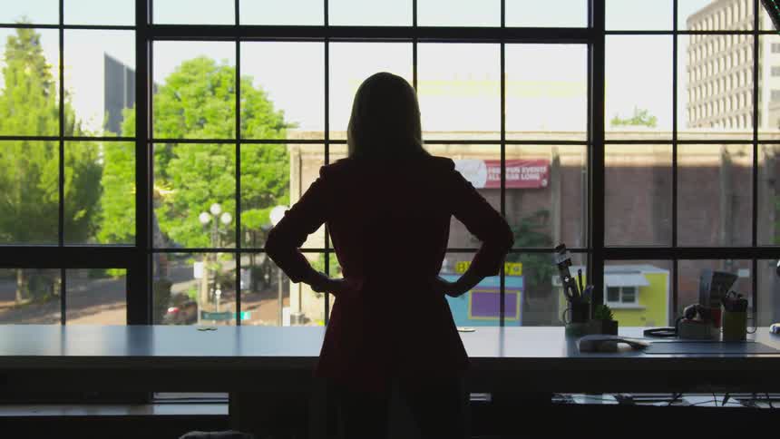 A silhouette of a woman standing in front of a window