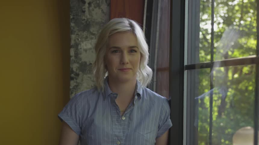 A woman stands in front of a window