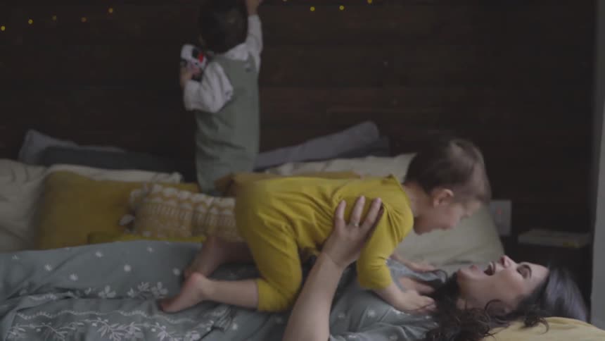 Children play with their mother on a bed
