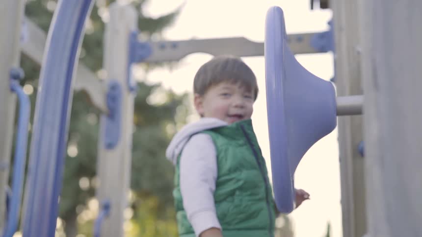 Boy wearing green vest playing in a playground