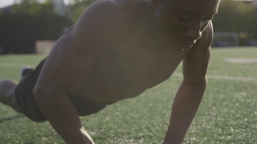 A man does push ups on a field